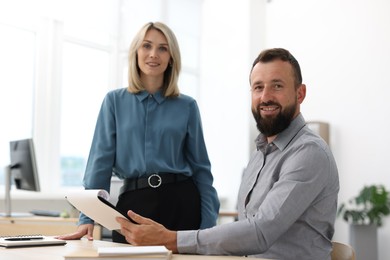 Photo of Portrait of smiling business partners with documents at table in office