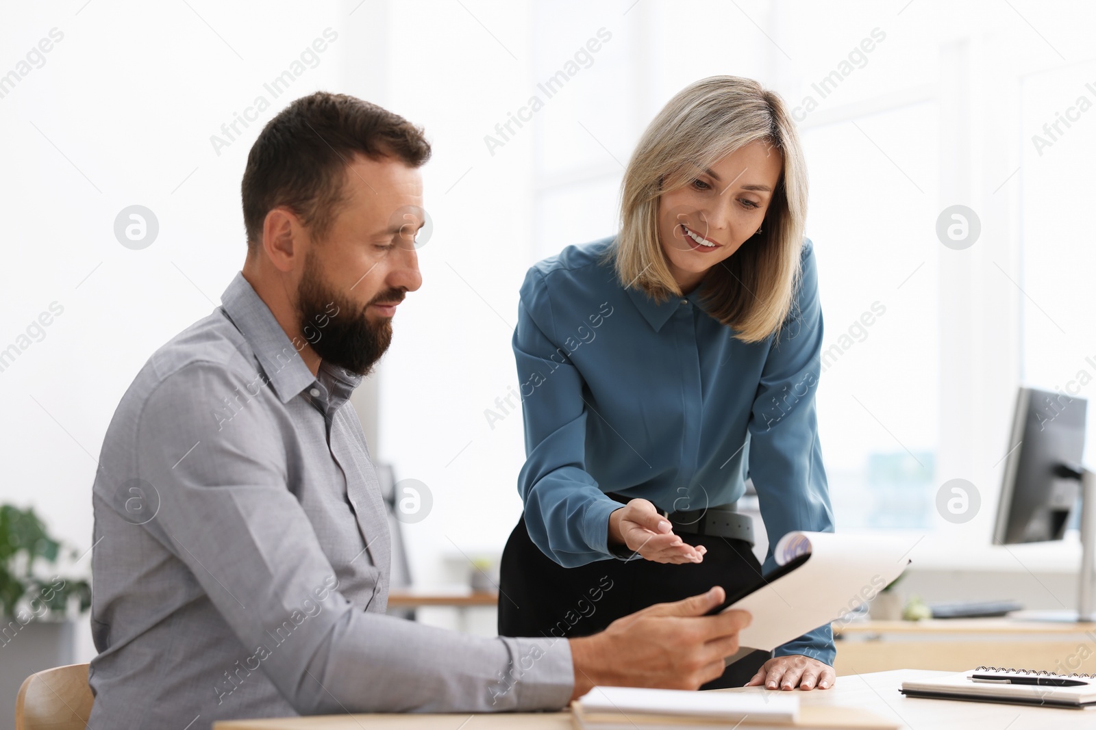 Smiling business partners working with documents at table in office Photo of Smiling business partners working with documents at table in office