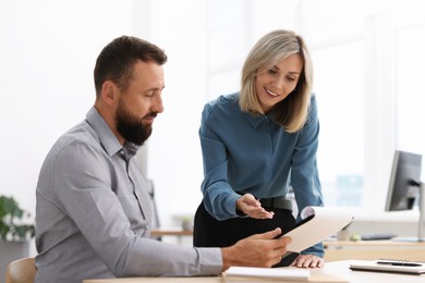 Photo of Smiling business partners working with documents at table in office