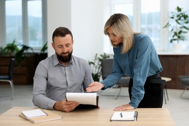 Photo of Business partners working with documents at table in office