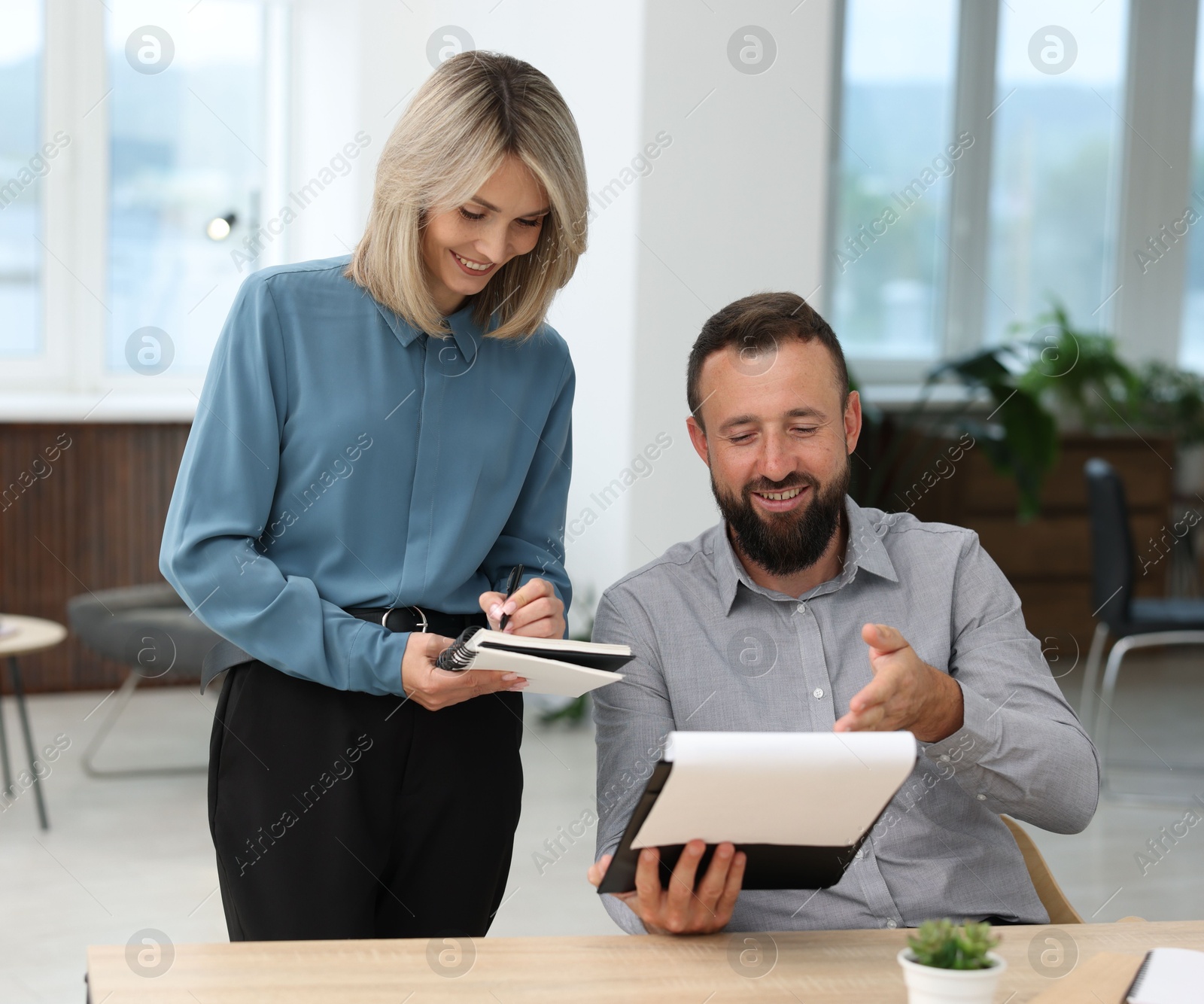 Photo of Smiling business partners working with documents at table in office