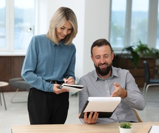 Photo of Smiling business partners working with documents at table in office