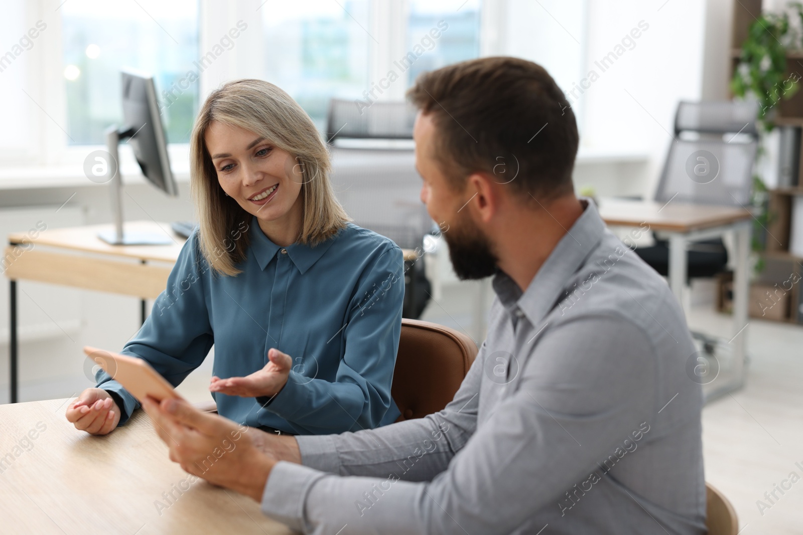 Photo of Smiling business partners working with tablet at table in office