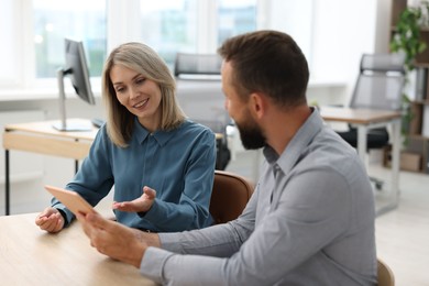 Photo of Smiling business partners working with tablet at table in office