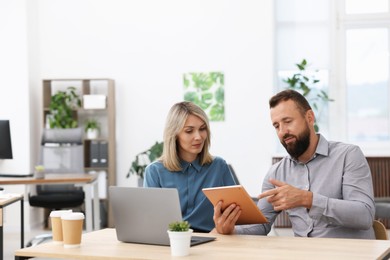 Photo of Business partners working with tablet at table in office