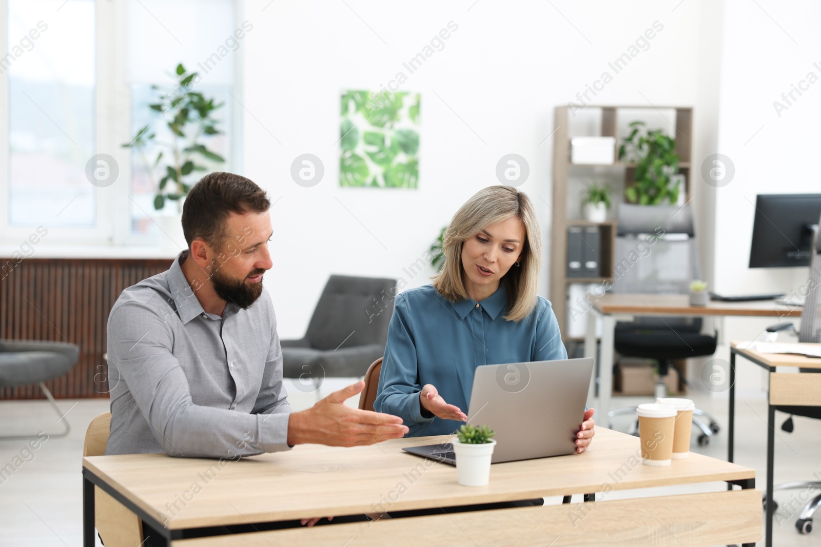Photo of Business partners working with tablet at table in office