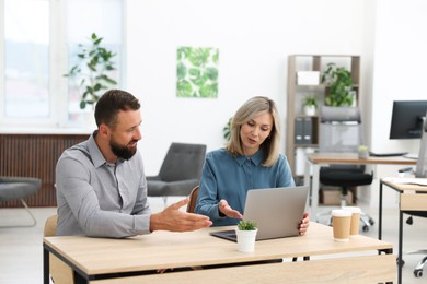 Photo of Business partners working with tablet at table in office