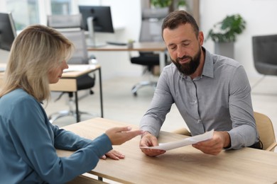 Photo of Business partners working with documents at table in office