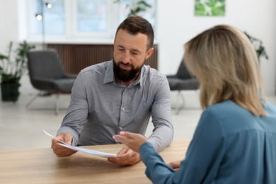 Photo of Business partners working with documents at table in office
