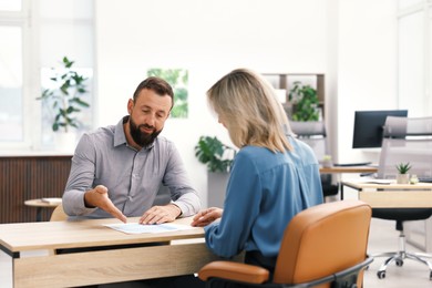 Photo of Business partners working with documents at table in office