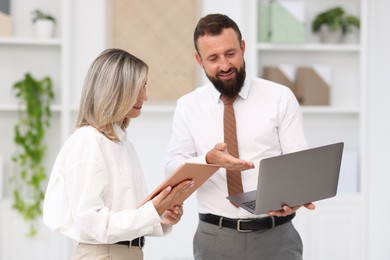 Photo of Smiling business partners working with devices in office