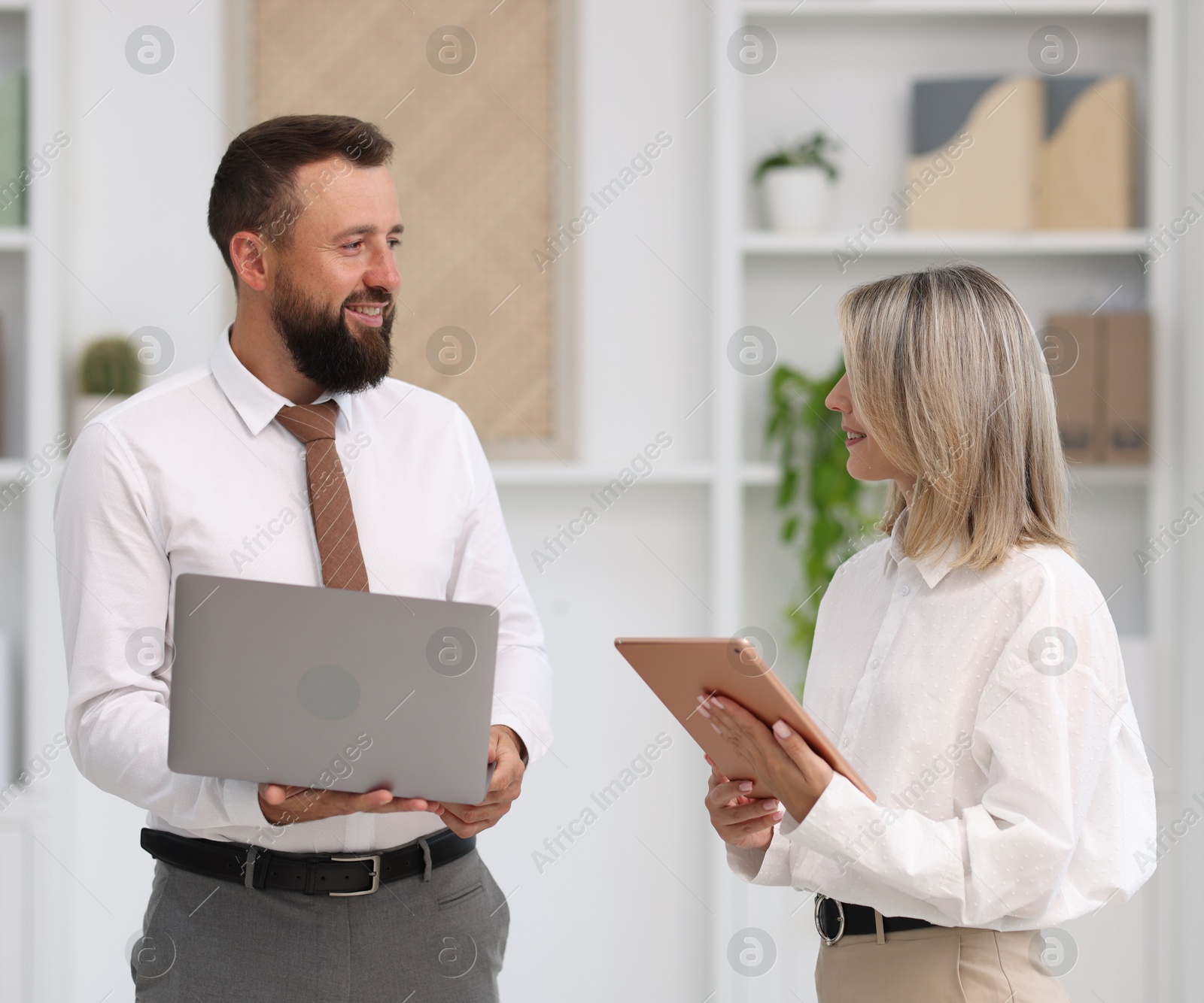 Photo of Smiling business partners with devices in office