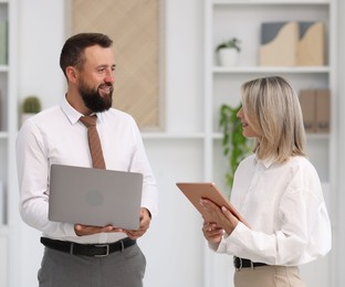 Photo of Smiling business partners with devices in office