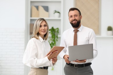 Photo of Portrait of smiling business partners with devices in office