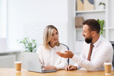 Photo of Business partners working with laptop at table in office