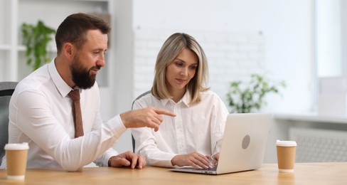 Photo of Business partners working with laptop at table in office