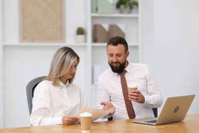 Photo of Smiling business partners working with documents at table in office