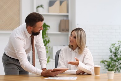Photo of Smiling business partners working with tablet at table in office