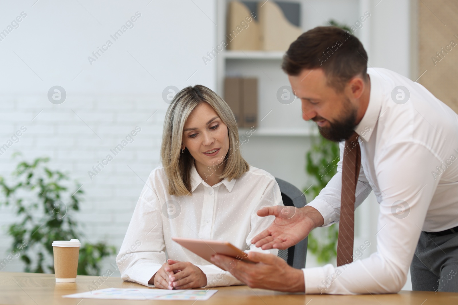 Photo of Smiling business partners working with tablet at table in office