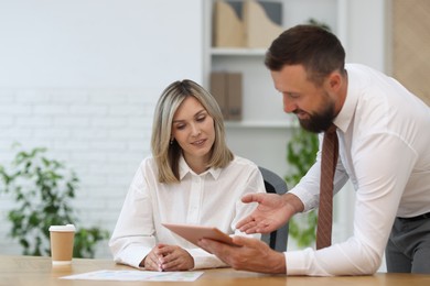 Photo of Smiling business partners working with tablet at table in office
