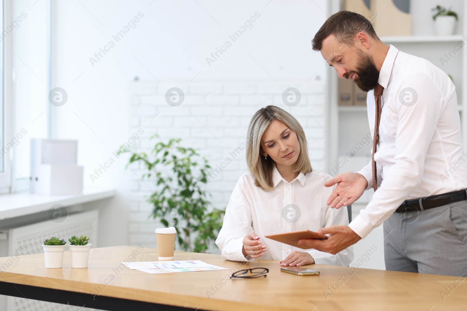 Photo of Business partners working with tablet at table in office
