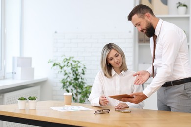 Photo of Business partners working with tablet at table in office