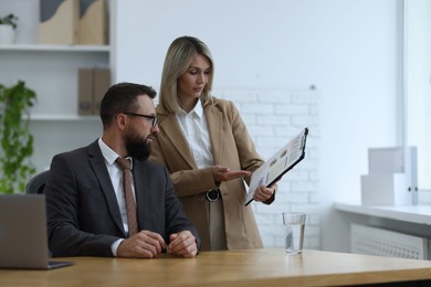 Photo of Business partners working with documents at table in office