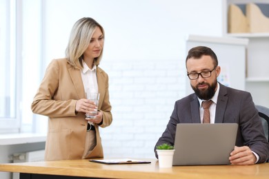 Photo of Business partners working with laptop at table in office
