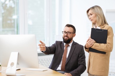 Photo of Business partners working with computer at table in office