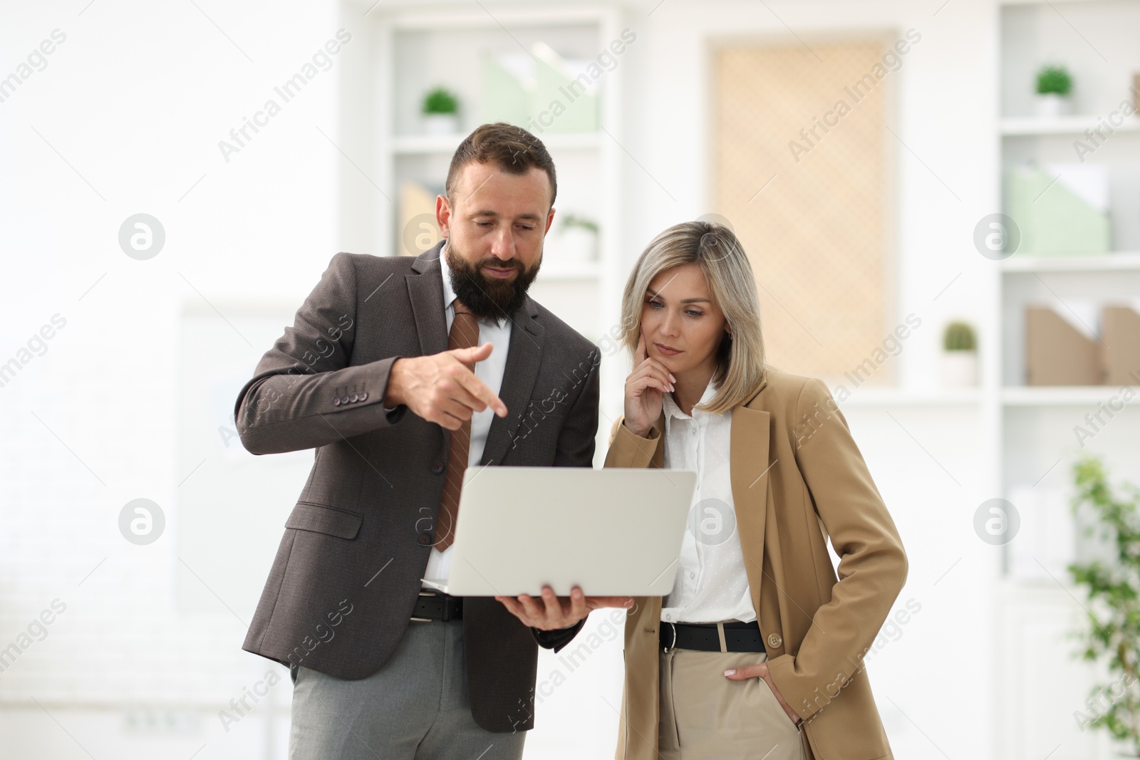 Business partners working with laptop in office Photo of Business partners working with laptop in office