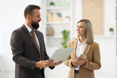 Photo of Smiling business partners working with devices in office