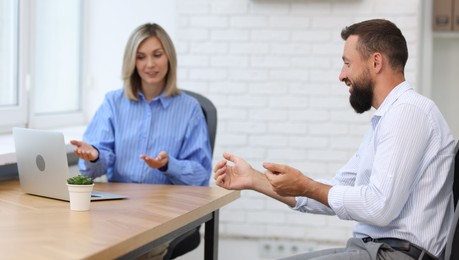 Photo of Smiling business partners working with laptop at table in office