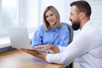 Photo of Smiling business partners working with laptop at table in office