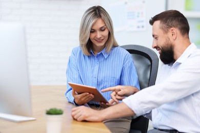 Photo of Smiling business partners working with tablet at table in office