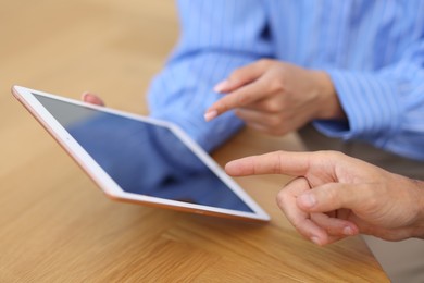 Photo of Business partners working with tablet at wooden table, closeup