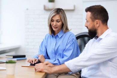 Photo of Smiling business partners working with tablet at table in office