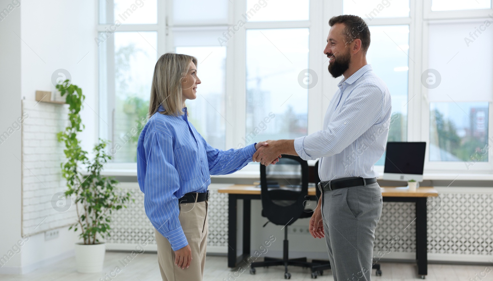 Smiling business partners shaking hands in office Photo of Smiling business partners shaking hands in office