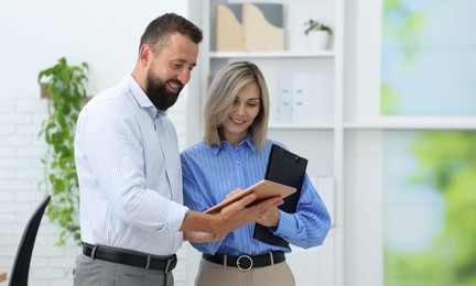 Photo of Smiling business partners working with tablet in office