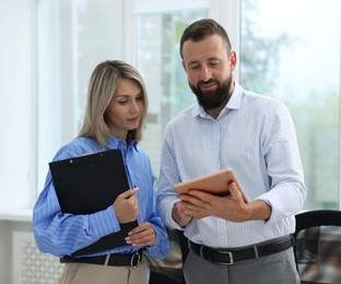 Photo of Business partners working with clipboard and tablet in office