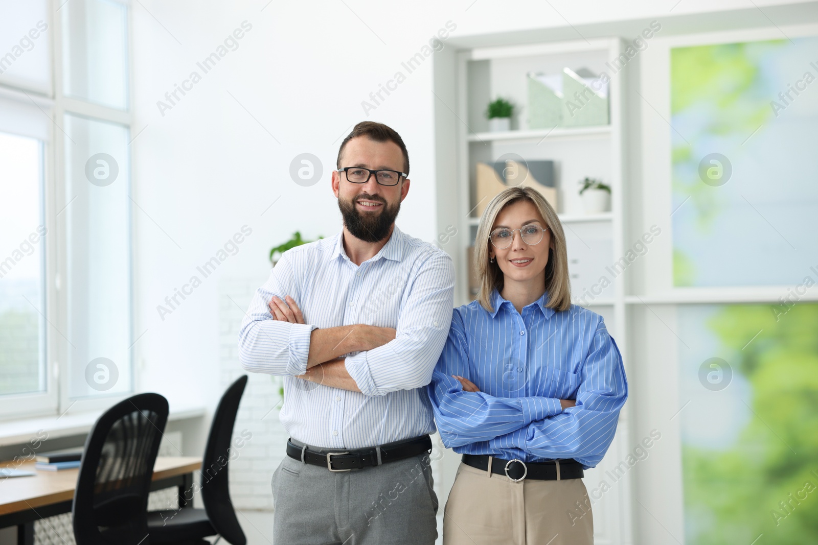 Portrait of smiling business partners in glasses with crossed arms in office Photo of Portrait of smiling business partners in glasses with crossed arms in office