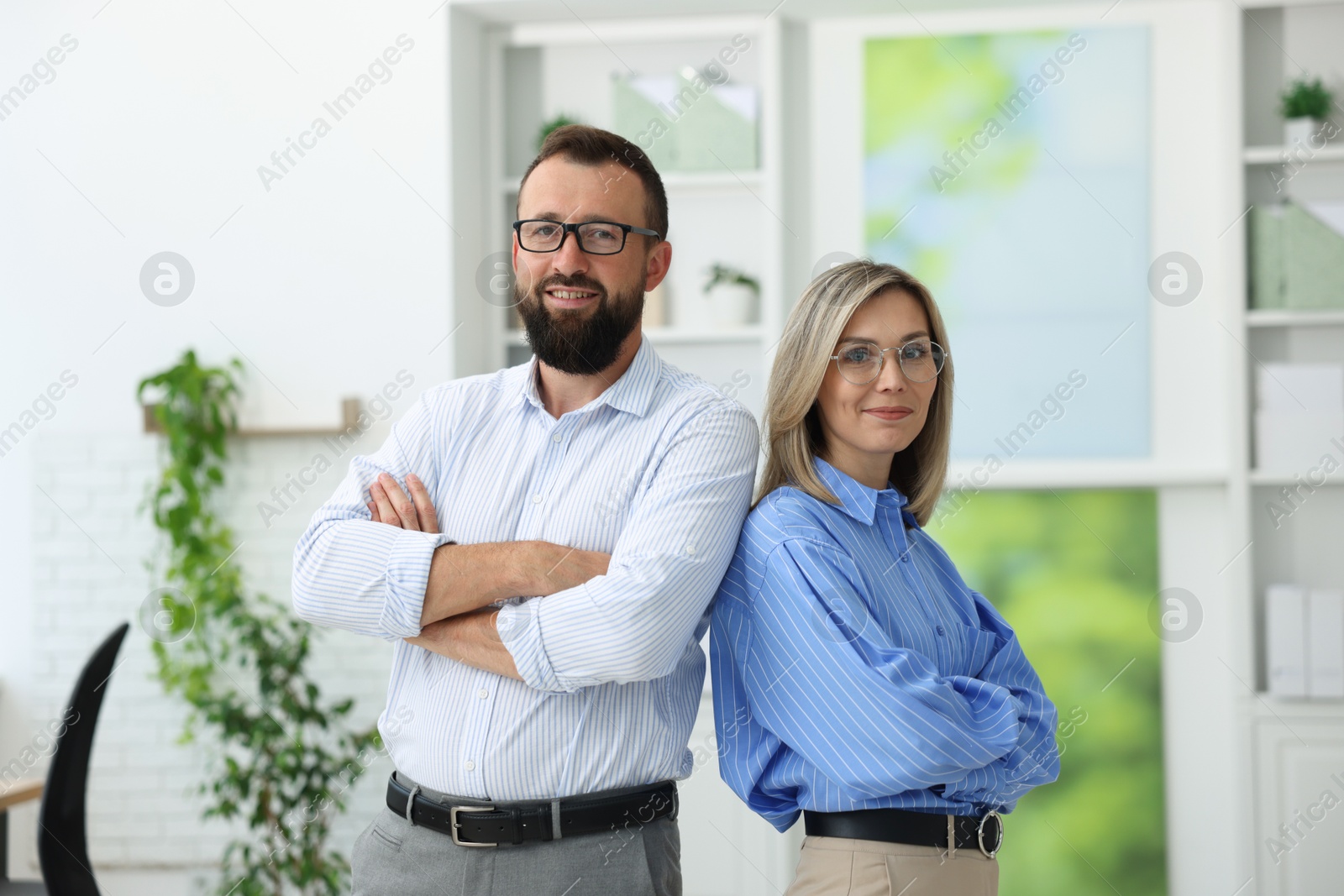 Portrait of smiling business partners in glasses with crossed arms in office Photo of Portrait of smiling business partners in glasses with crossed arms in office