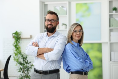 Photo of Portrait of smiling business partners in glasses with crossed arms in office