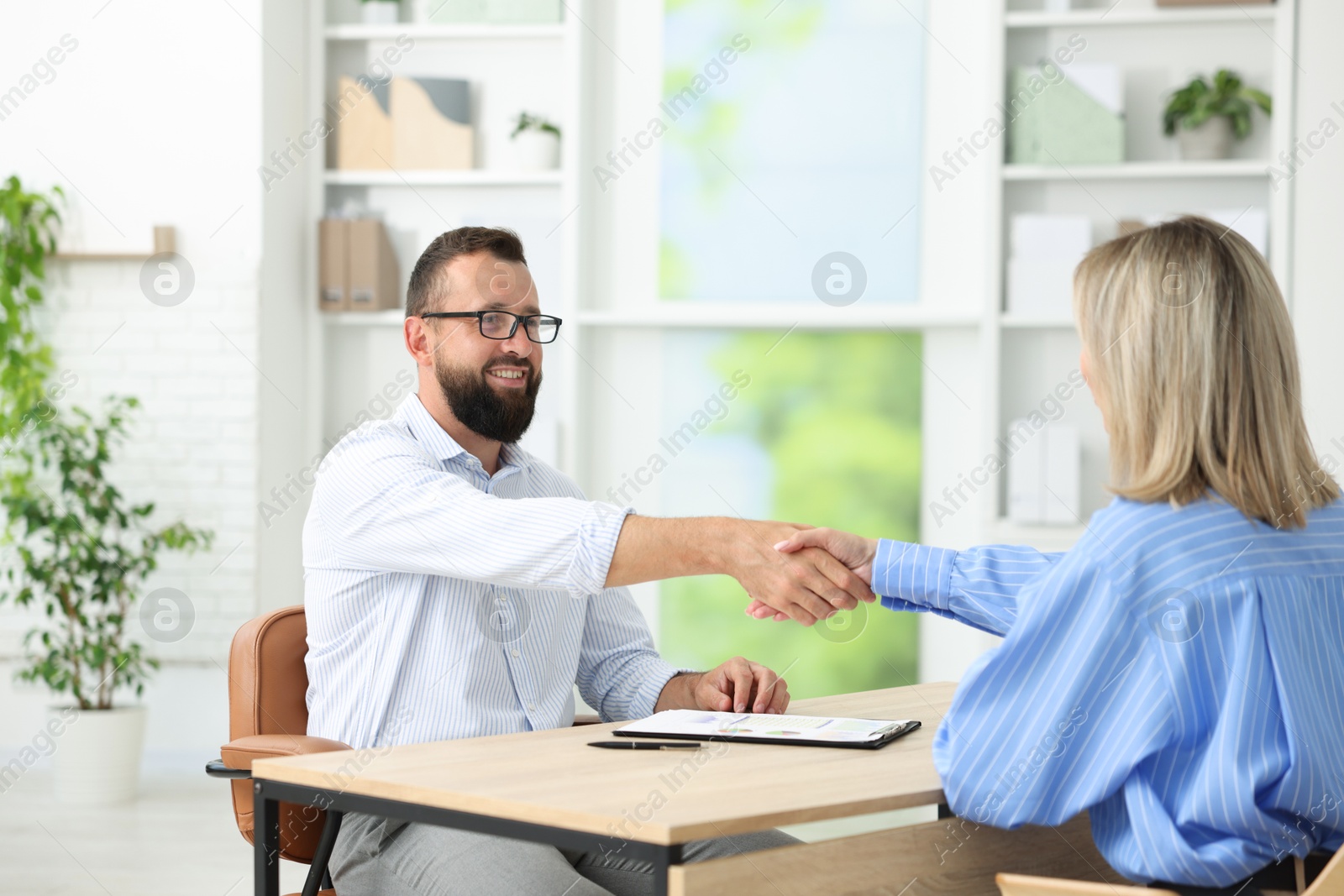 Photo of Business partners shaking hands at table in office