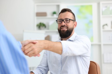 Photo of Business partners shaking hands at table in office, closeup