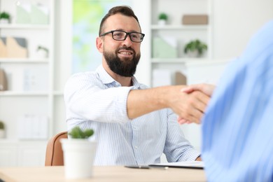 Photo of Business partners shaking hands at table in office, closeup
