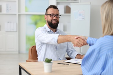 Photo of Business partners shaking hands at table in office, closeup