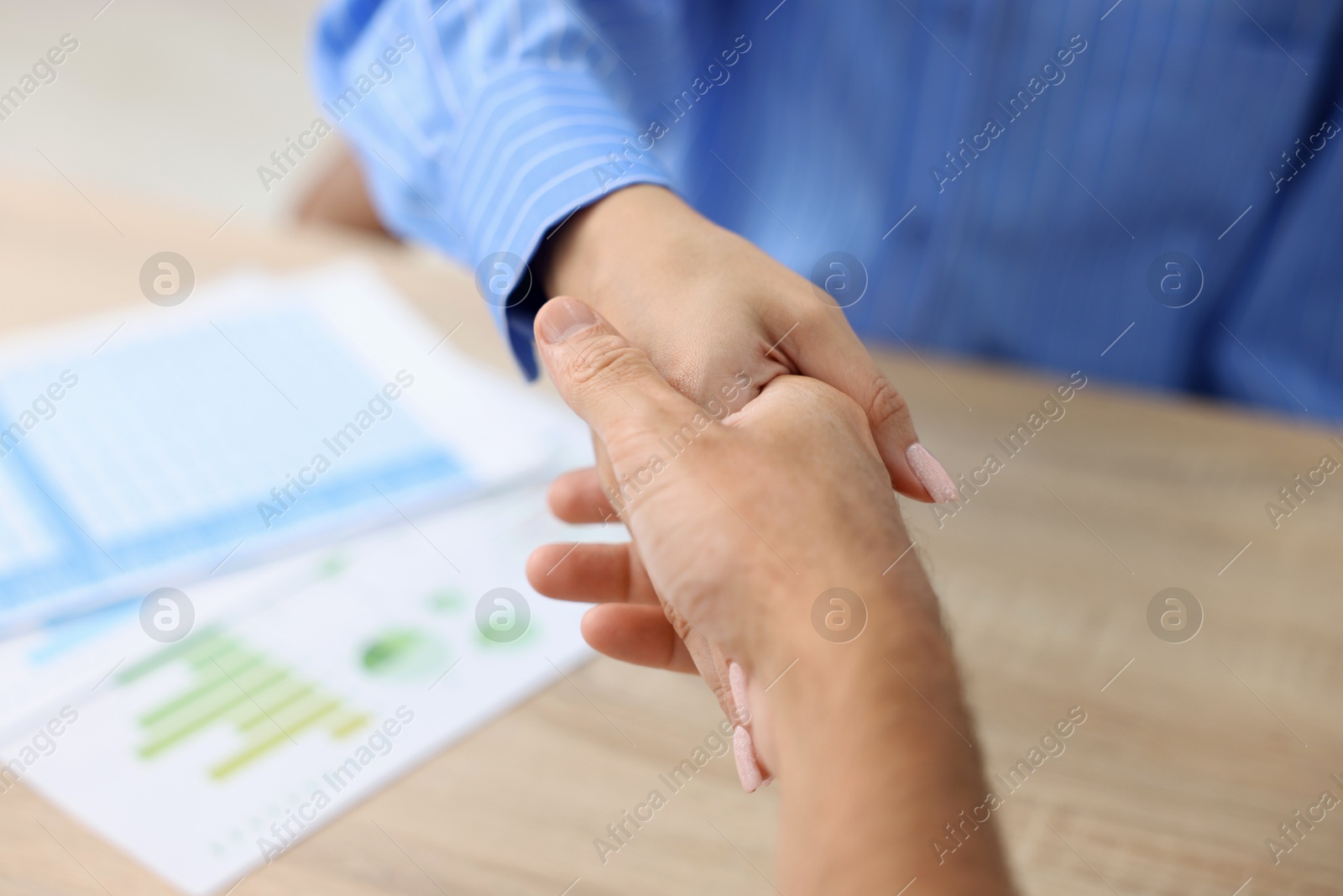 Business partners shaking hands at table, closeup Photo of Business partners shaking hands at table, closeup