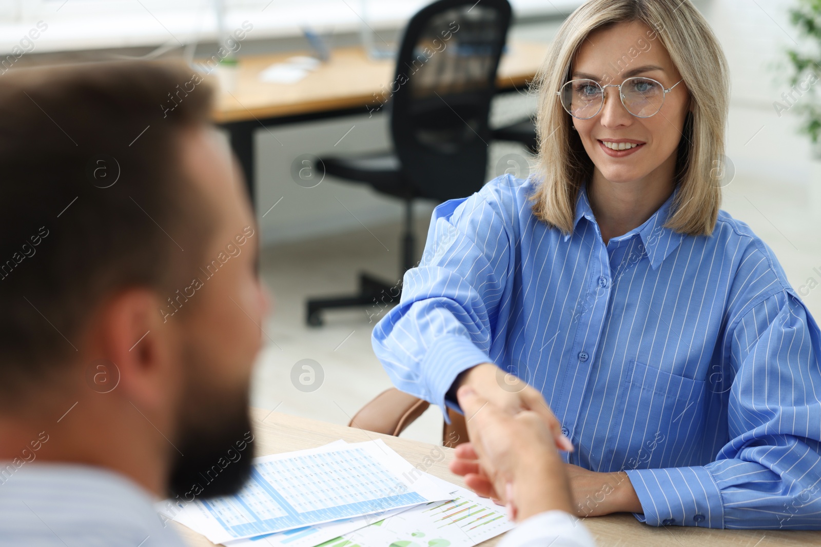 Photo of Business partners shaking hands at table in office