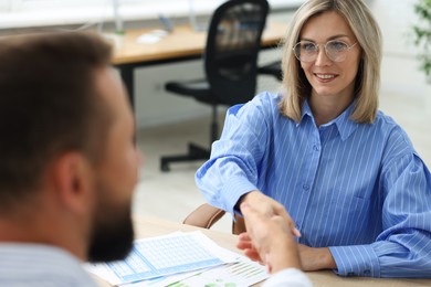 Photo of Business partners shaking hands at table in office