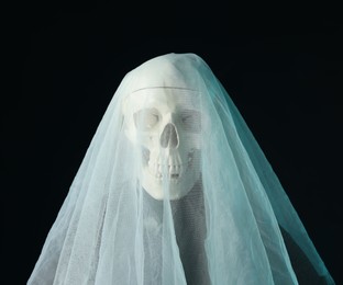 Photo of Creepy ghost. Skeleton covered with white sheet on black background